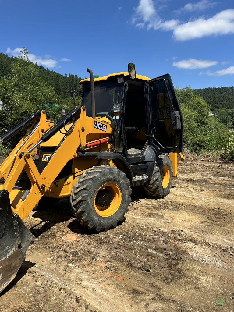 Traktorbager JCB 3CX Compact pripravený na zemné práce a úpravy terénu na stavebnom pozemku. Vhodný pre výkopové práce a manipuláciu s pôdou, tento kompaktný stroj je ideálny pre stavebné projekty spoločnosti po-bagrujem.sk.