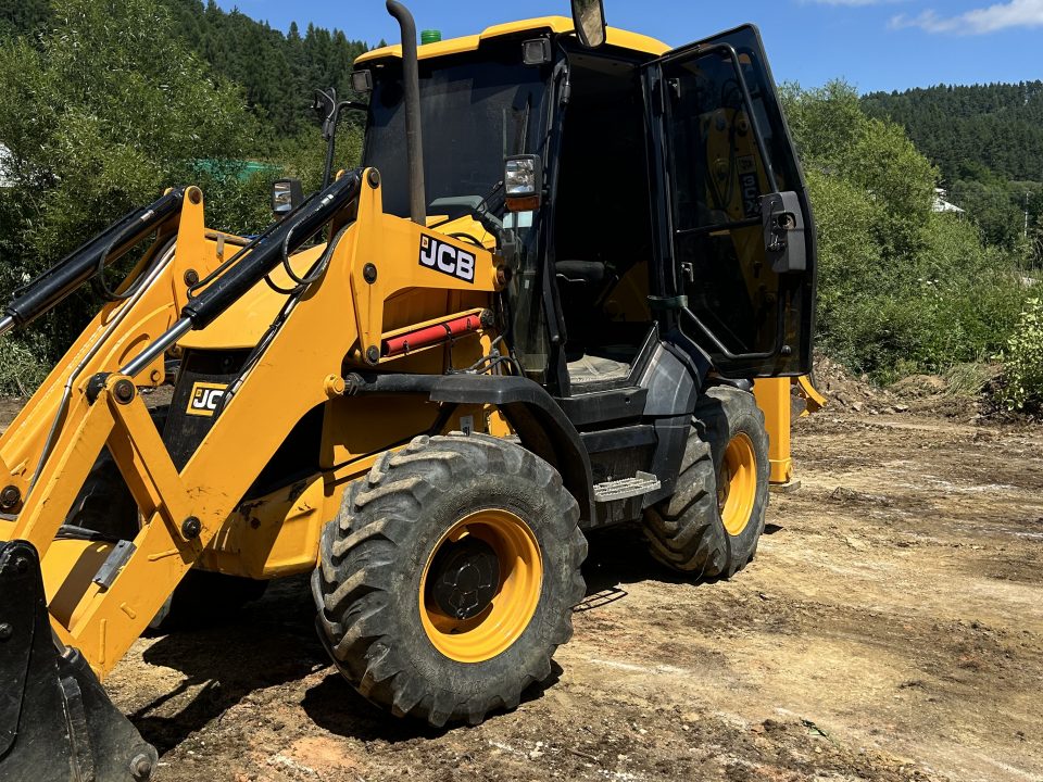 Traktorbager JCB 3CX Compact pripravený na zemné práce a úpravy terénu na stavebnom pozemku. Vhodný pre výkopové práce a manipuláciu s pôdou, tento kompaktný stroj je ideálny pre stavebné projekty spoločnosti po-bagrujem.sk.